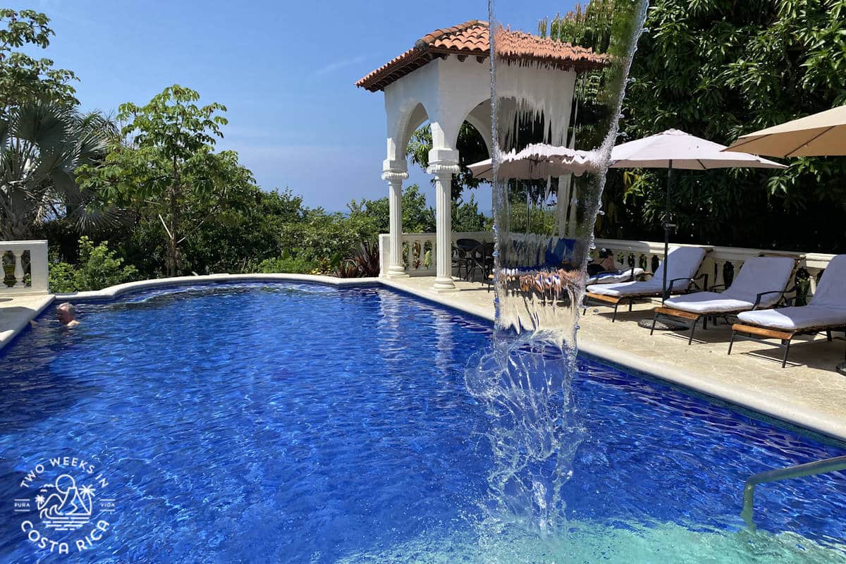 pool with fountain and lounge chairs along the edge