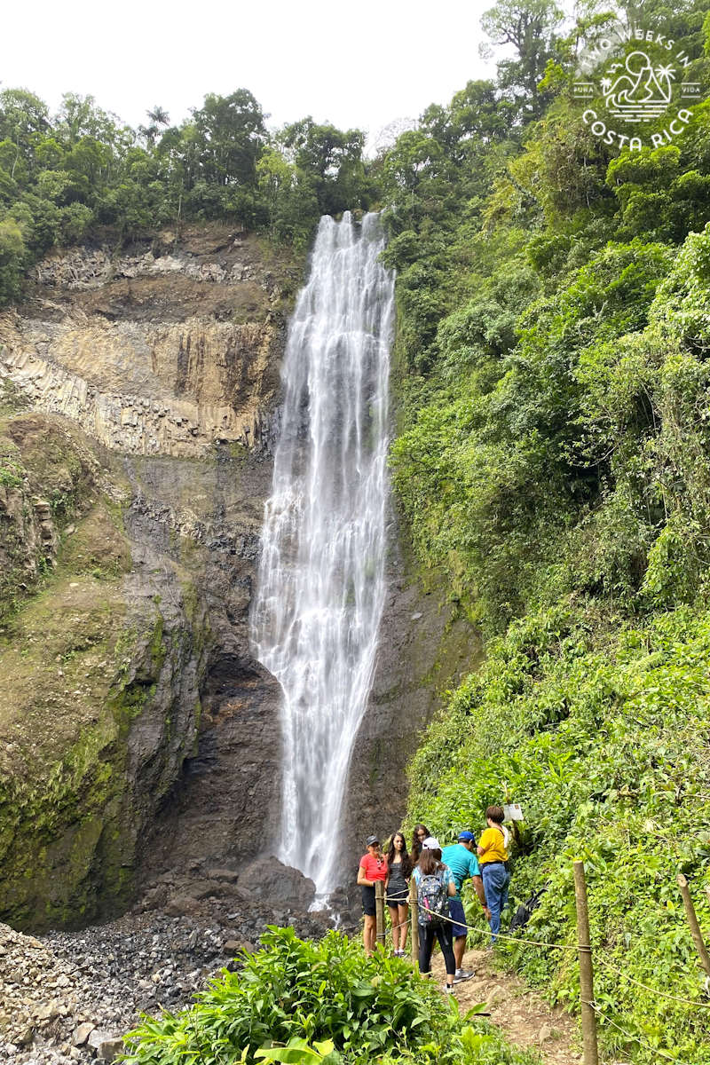people on a trail looking at a large waterfall