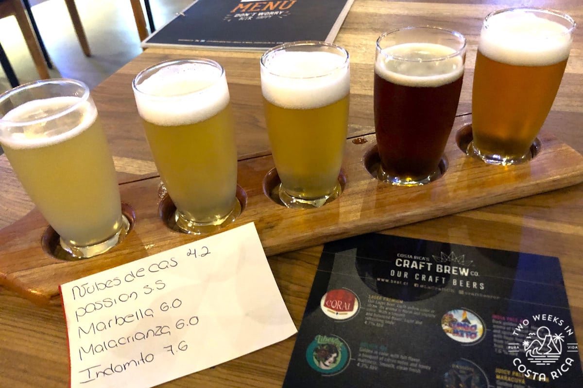 A flight of beer on a table with papers and a menu