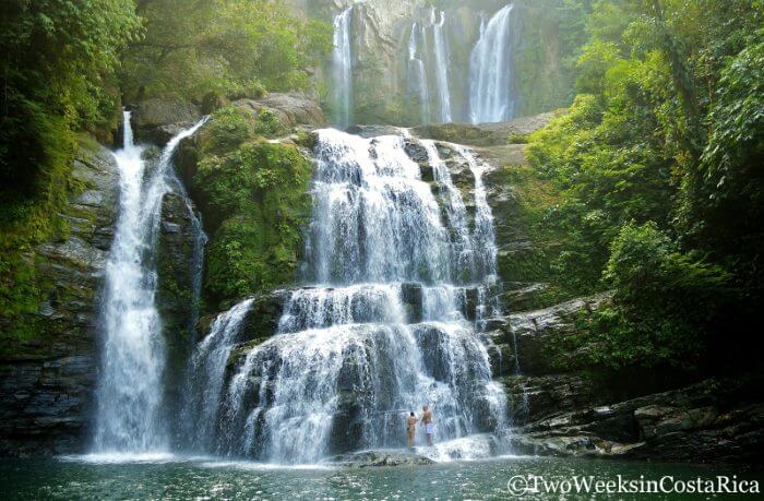 Large wide waterfall in jungle with a couple