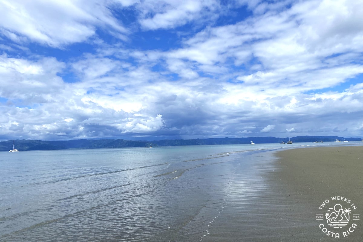 beach with clear calm water and a blue sky with pretty clouds