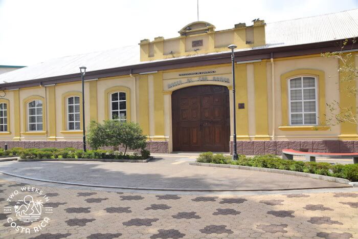 A yellow historical building with paver walkway in front