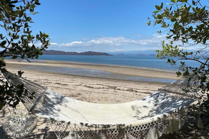 hammock over sand near calm bay mountain background