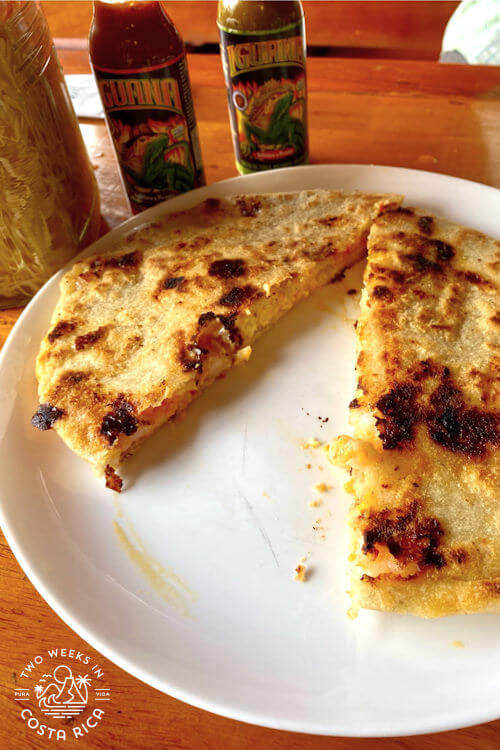 corn meal pancake with shrimp cut in center with hot sauce in background