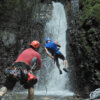 guide helping someone rappel down a large waterfall