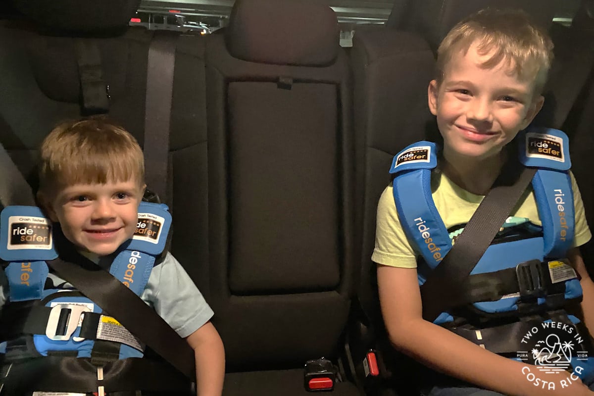 Two children wearing Ride Safer vests as a substitute for a regular car seat