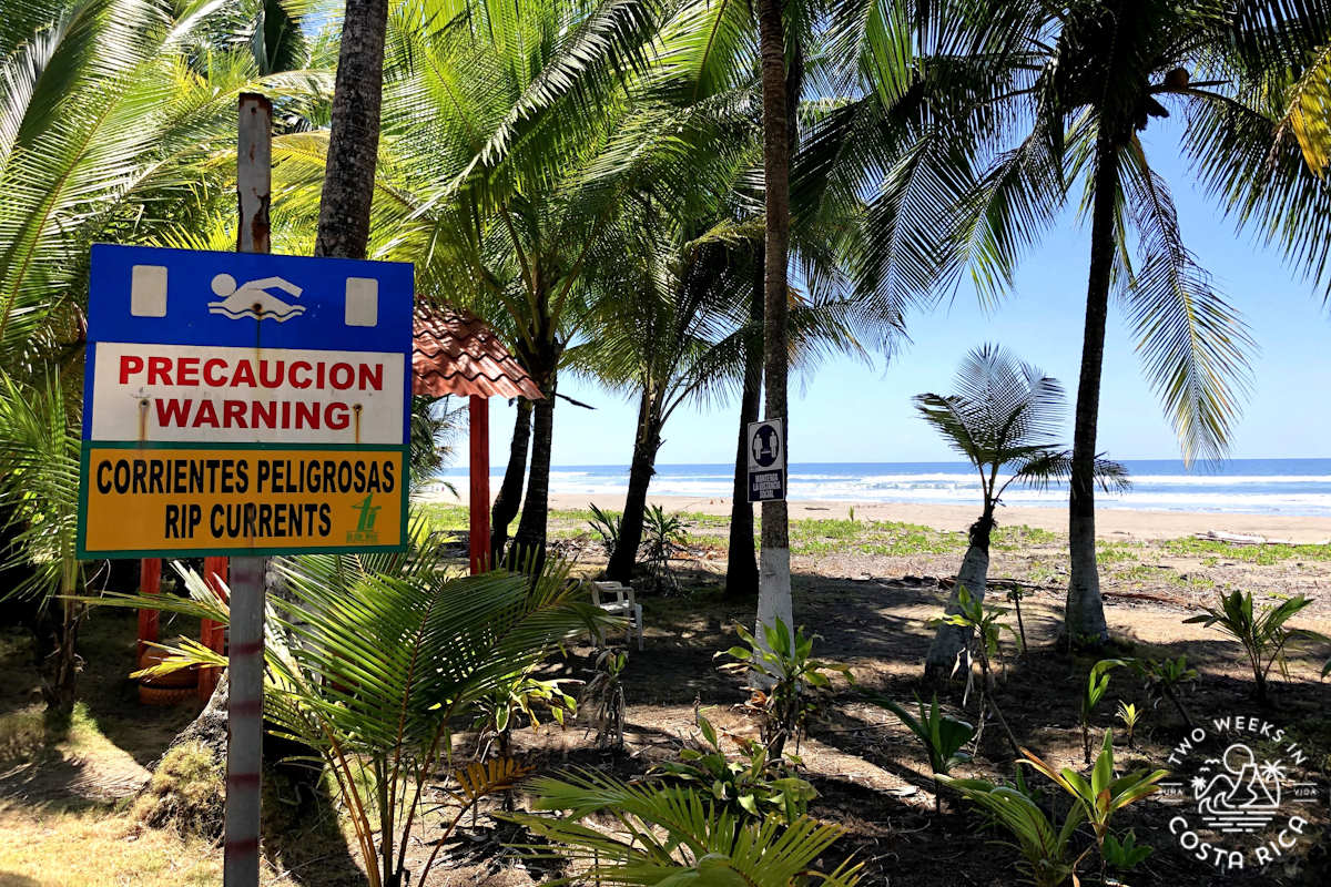 a beach with a sign that says warning rip currents