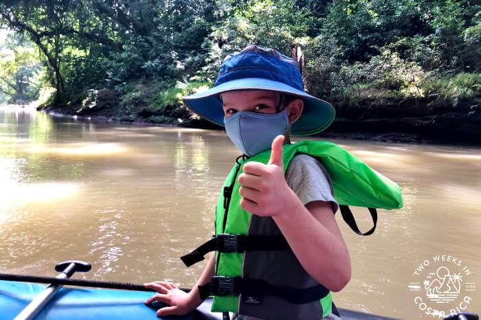 A young boy sitting in a river raft on the penas blancas river in Costa Rica giving the thumbs up signal