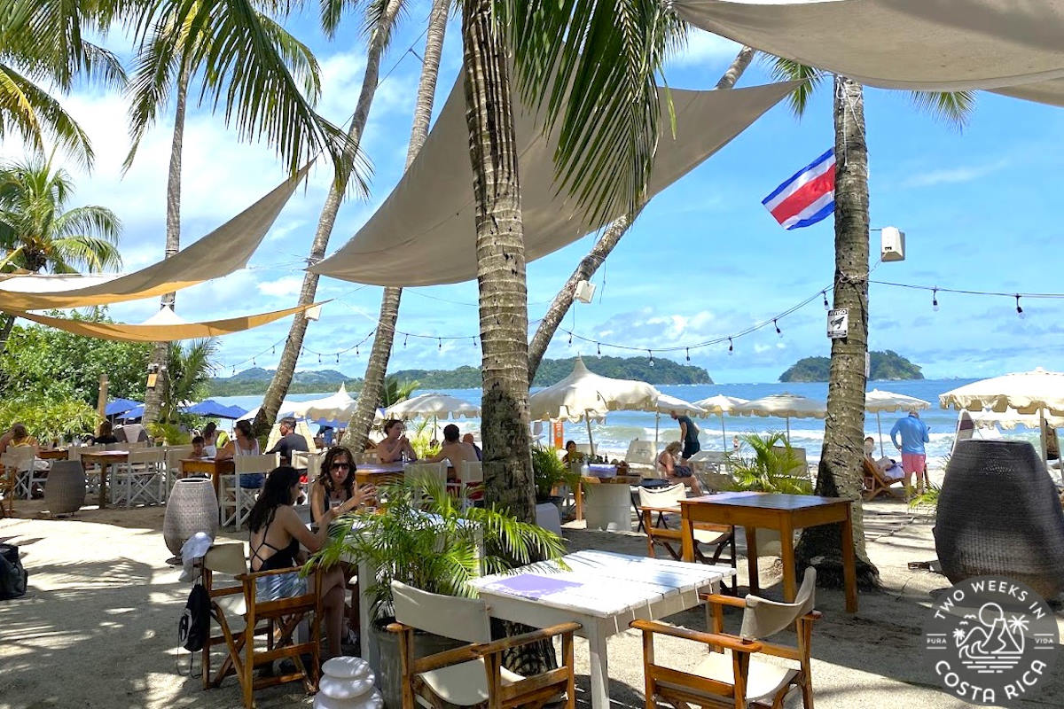 Restaurant tables set up under palm trees on Samara Beach