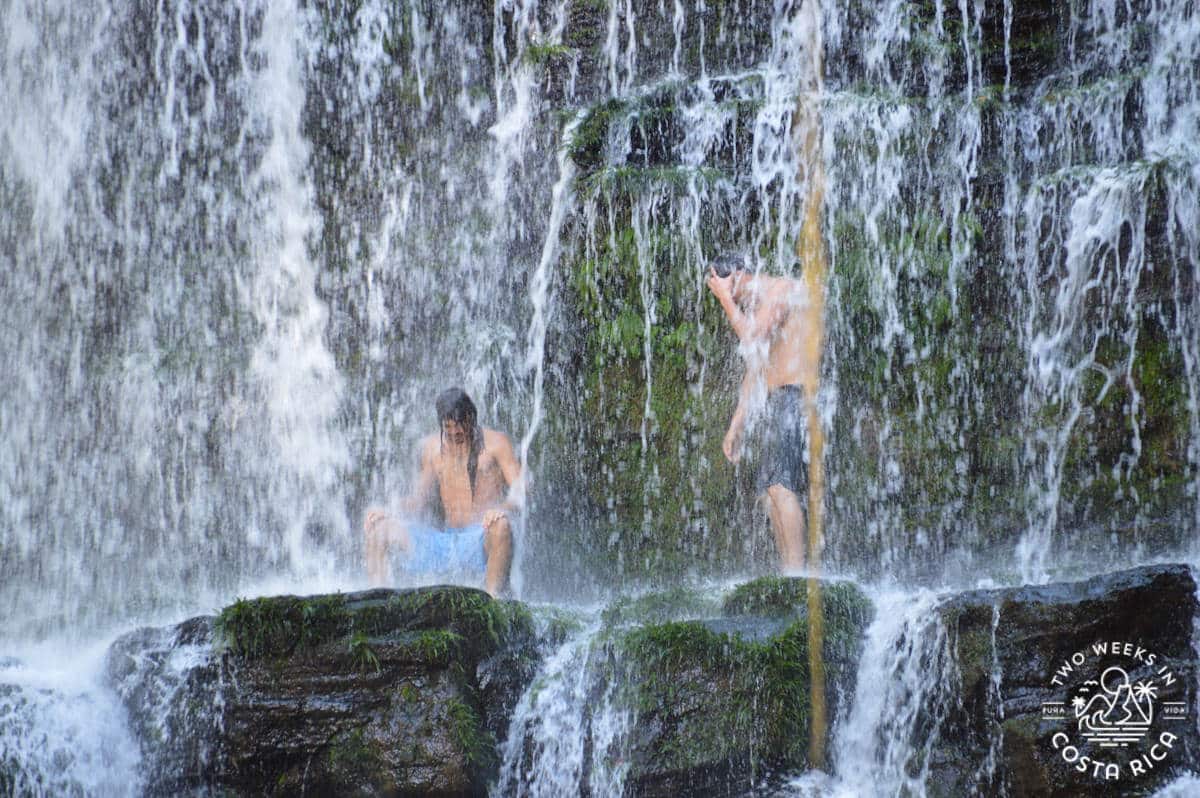 a group of guys standing under the nauyaca waterfall