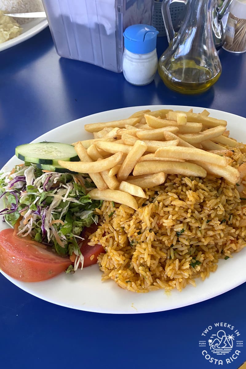 a plate of food with rice, french fries and salad