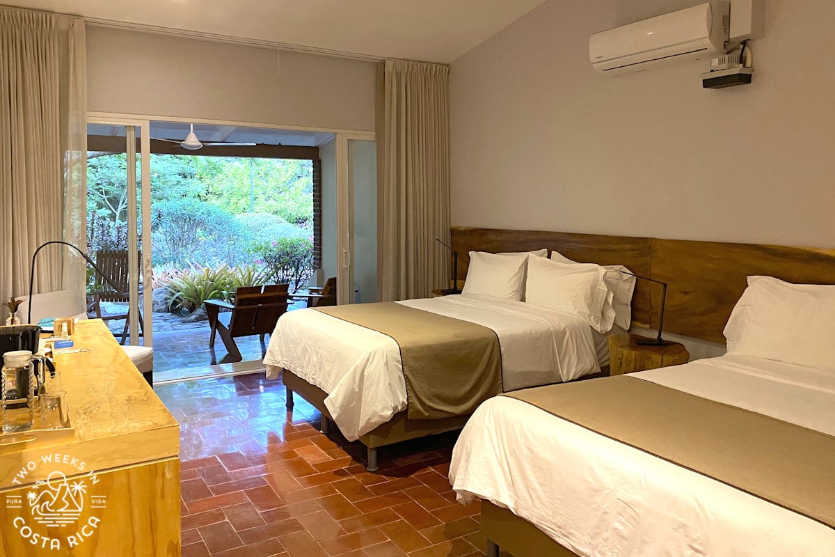 a hotel room with two beds and a large terrace overlooking gardens