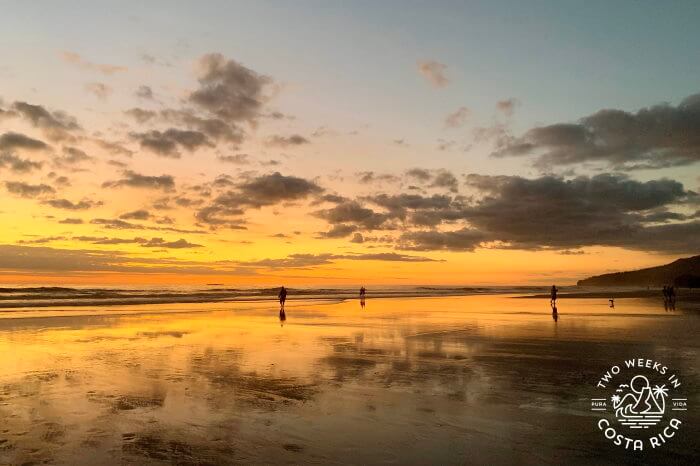 People on the beach at sunset with an orange sky