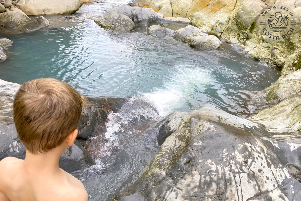 a kid standing on rocks at the blue pools