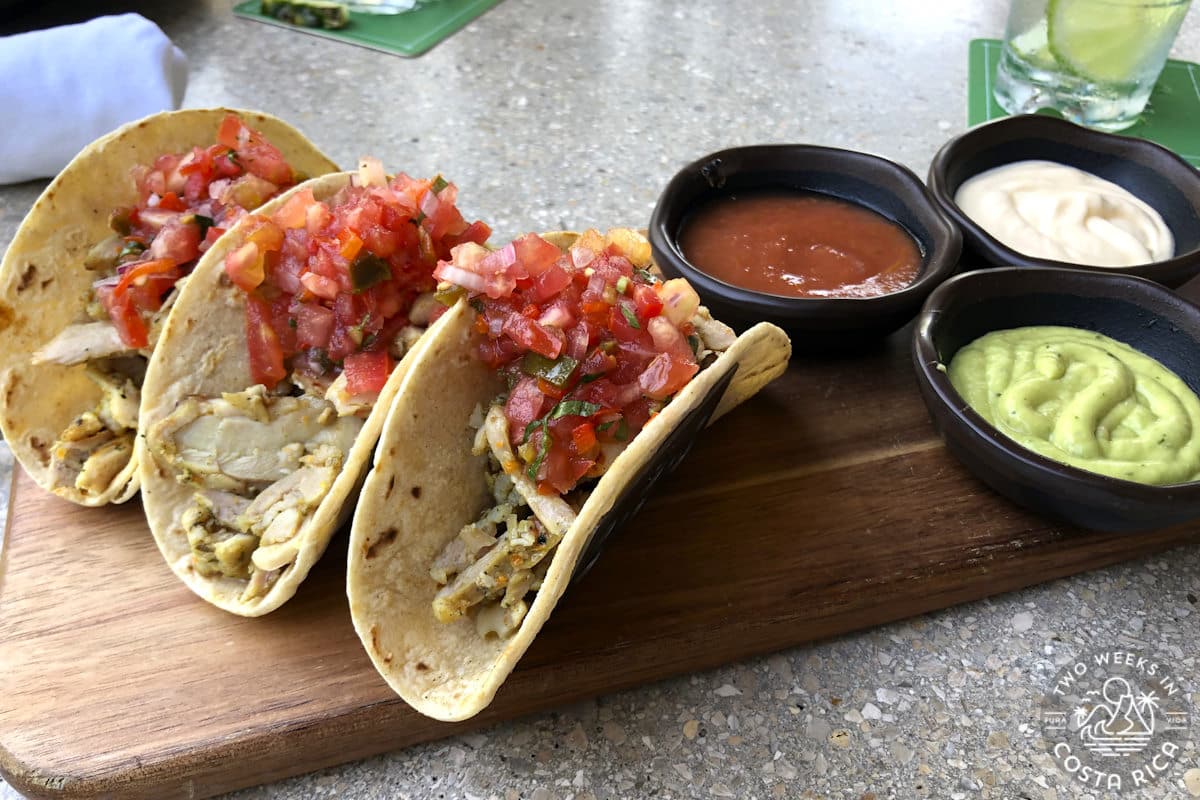 three tacos with salsa on a wooden board