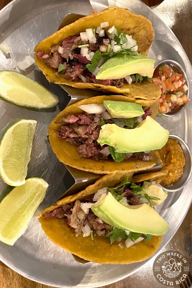 Three tacos with a side of limes