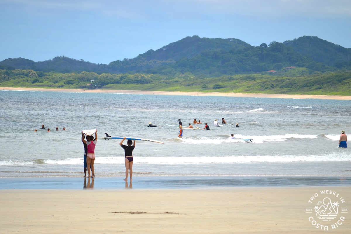 Teenagers holding surfboard above their heads on Tamarindo Beach in Costa Rica