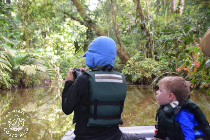 Two young boys with life jackets on at the front of a boat during a tour of Tortuguero National Park's canals