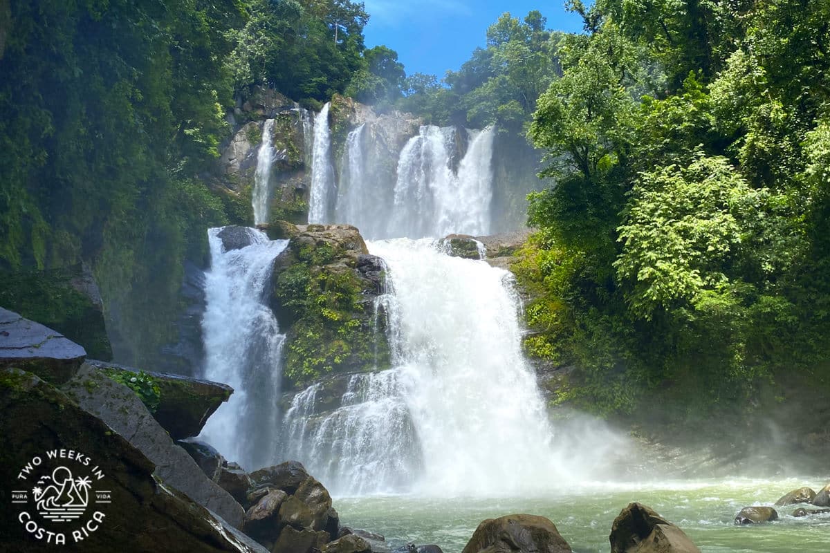 a waterfall with two levels surrounded by rainforest