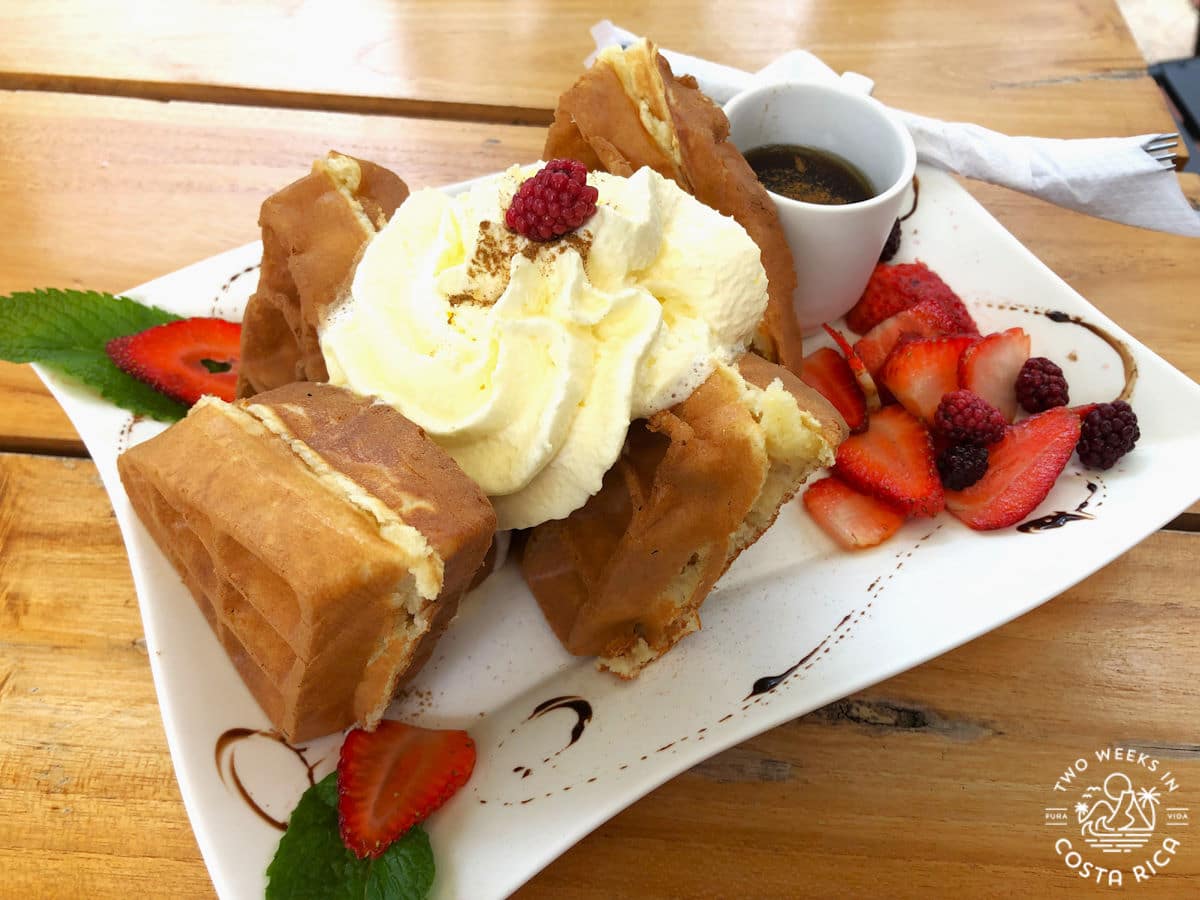 A plate of waffles with ice cream and strawberries